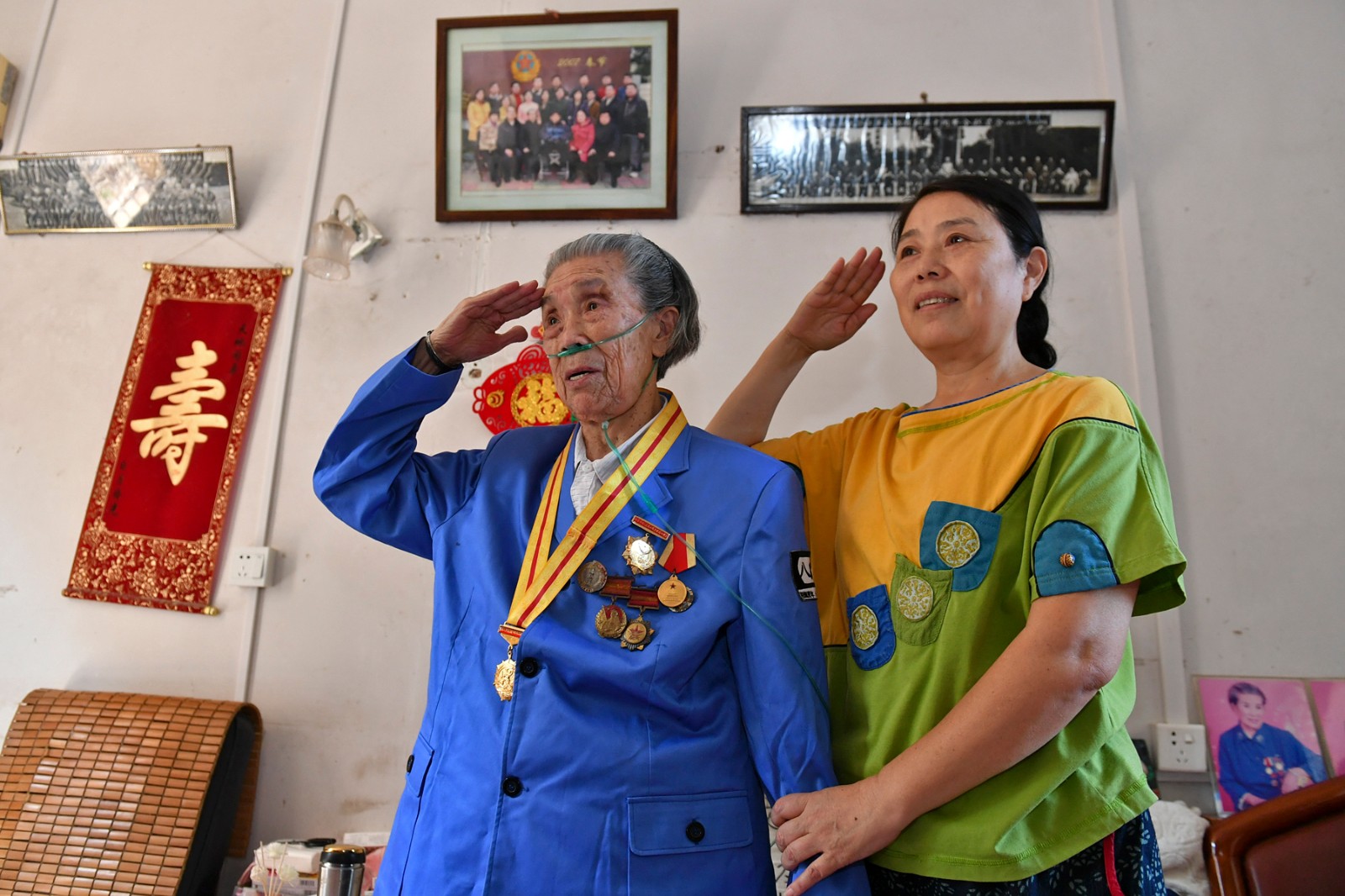 閱兵式進行中，余新華（左）和女兒對著電視機屏幕敬了個軍禮,。