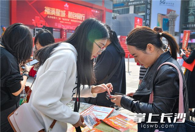 一位女士正在掃二維碼參與消費節(jié)系列優(yōu)惠活動。