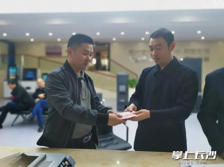 申請執(zhí)行人接過執(zhí)行法官手中的執(zhí)行款。湖南高院供圖