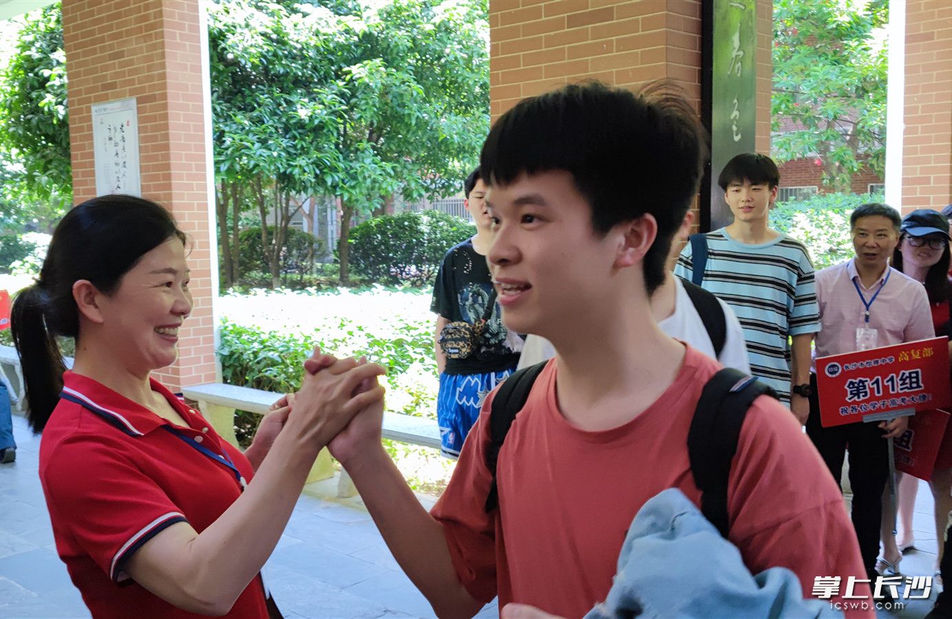 一名考生走出考點(diǎn)后,，與付朝霞擊掌慶祝。均為通訊員 李勛亮 供圖