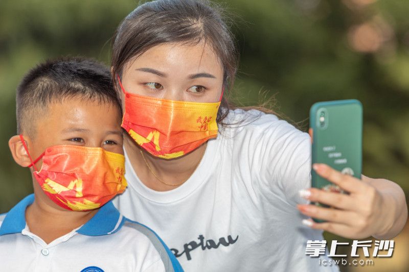 一位母子正在自拍,，口罩上寫著“我愛你中國”。