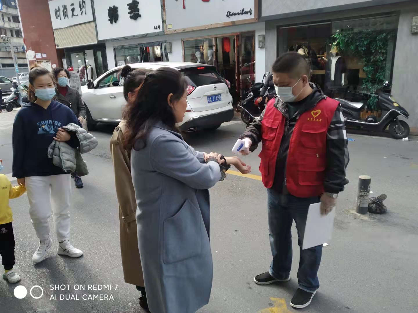 “紅馬甲”正在為顧客量體溫,。全媒體記者 顏家文攝