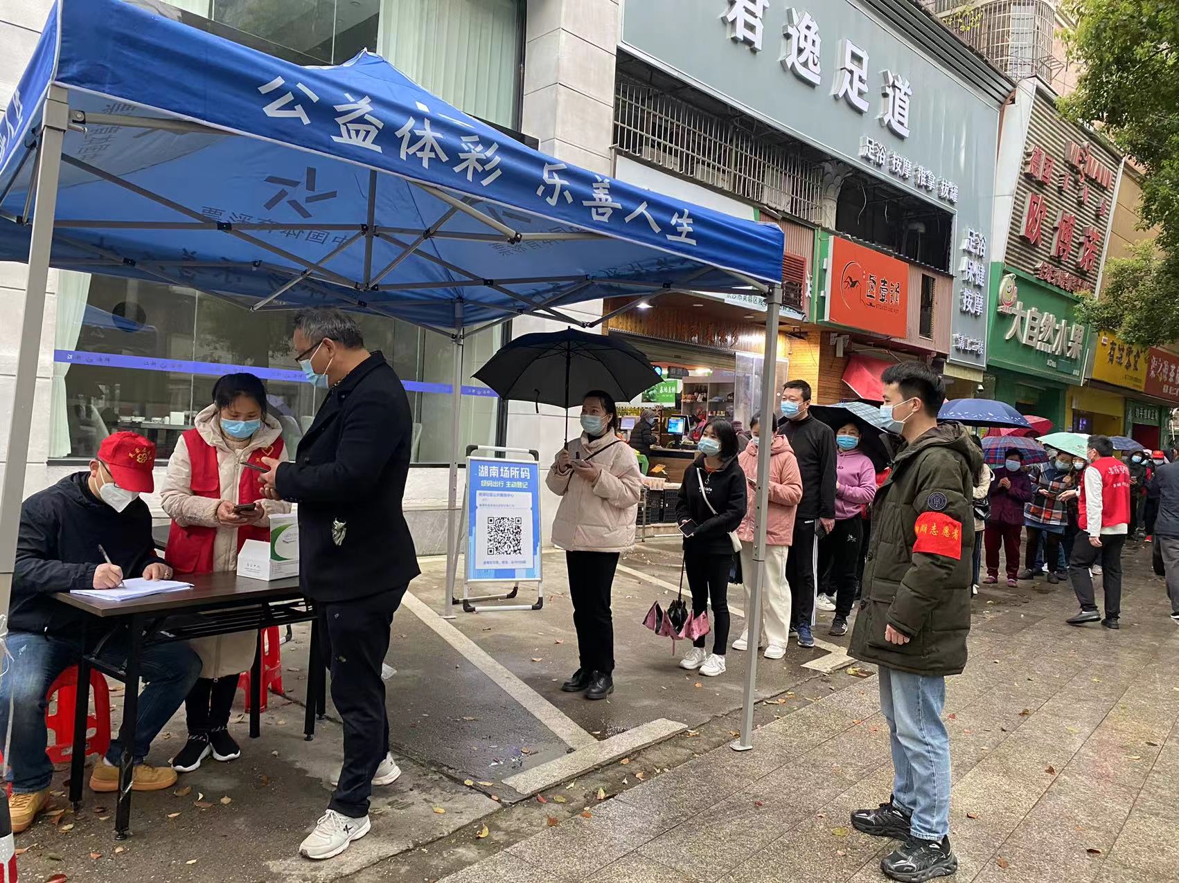 蔣戀峰（右一）正在社區(qū)核酸采樣點維持秩序,。受訪單位供圖