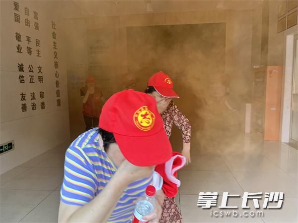 黨員志愿者捂住口鼻從消防通道模擬逃生,。
