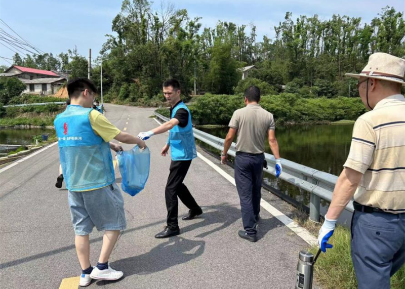 黨員志愿者在撿拾河道附近的垃圾,。