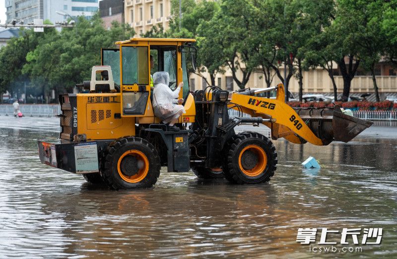 五一大道曉園路口一輛鏟車帶著去火車站趕車的乘客渡過(guò)積水區(qū),。