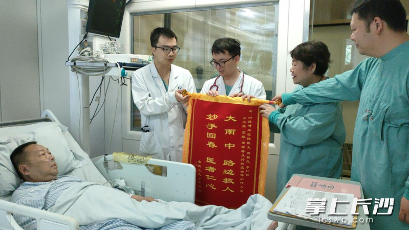 蔡大爺?shù)睦习辇從棠毯蛢鹤訉㈠\旗交到醫(yī)生手中,。 長(zhǎng)沙晚報(bào)全媒體記者 徐媛 實(shí)習(xí)生 譚仕蘭 攝