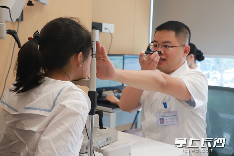 開學前,，不少家長帶著孩子來到長沙愛爾眼科醫(yī)院兒童眼科中心做視力檢查,，溫龍波（右）正在為孩子檢查視力。 均為通訊員供圖