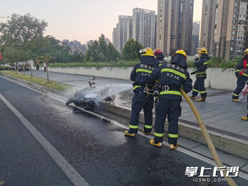 圖為消防隊員為冒煙的電動摩托車?yán)鋮s降溫。長沙晚報通訊員供圖