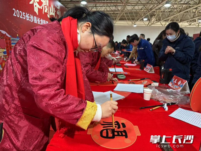 來自長沙市書法家協(xié)會、長沙經(jīng)開區(qū)書法家協(xié)會,、山河智能書法家協(xié)會的老師正在手寫春聯(lián)和“?！弊帧? style=