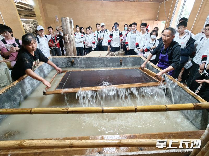 參觀了解瀏陽手工竹紙制作工坊,，學(xué)生們與手藝人趙尚兵共同抄紙。
