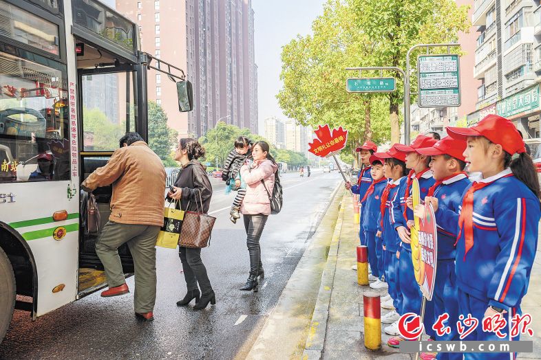 雨花區(qū)石壩路公交站臺邊，來自雨花區(qū)楓樹山大橋小學(xué)的孩子們舉著排隊禮讓宣傳牌,，向等候公交的市民宣傳排隊禮讓,。　長沙晚報全媒體記者 陳飛 攝