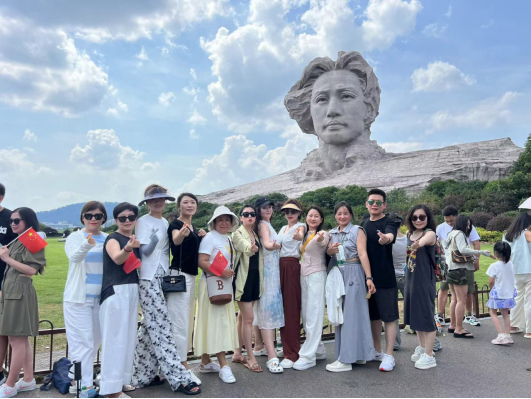 圖為本次團隊合影,。于卓廷將個人僅有的半天休息空檔，幫助游客預約協(xié)調(diào)并陪同來到橘子洲頭,，提供志愿講解,、拍攝等服務。